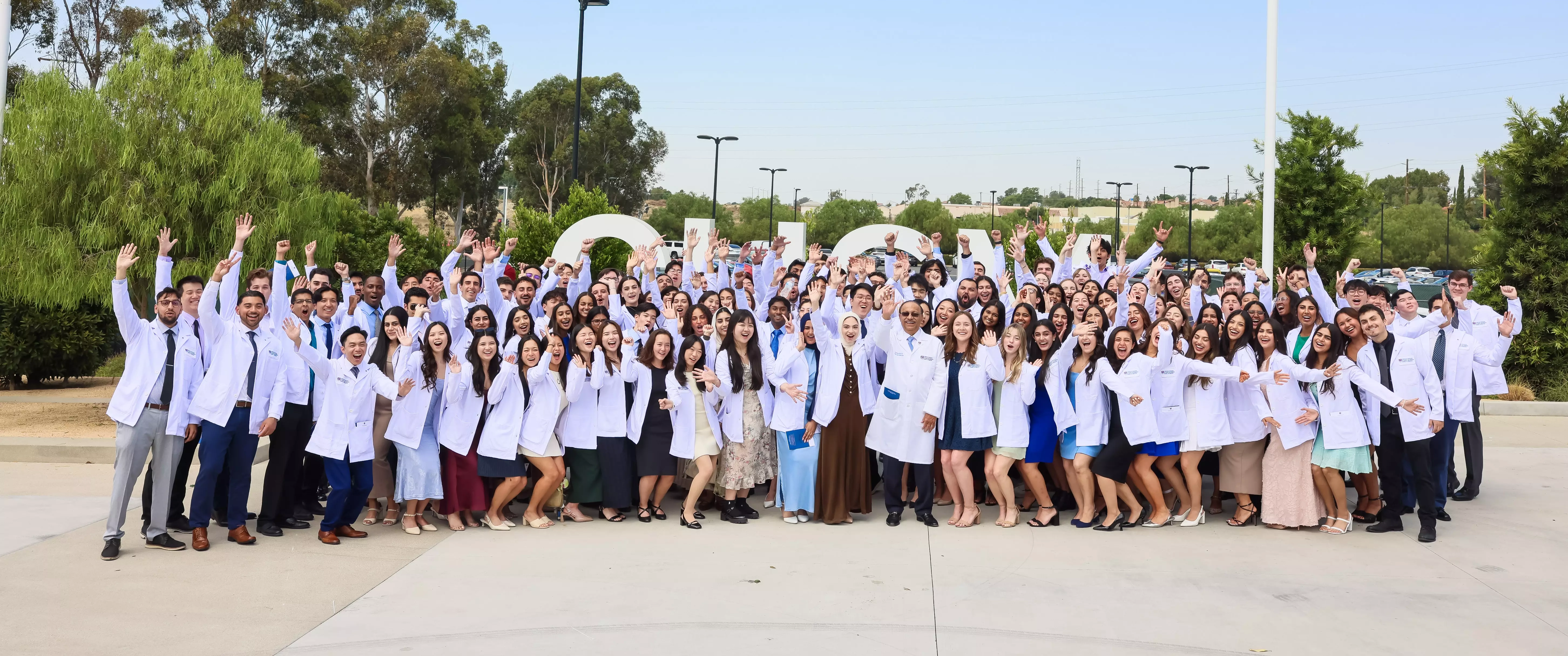 2026 White Coat Ceremony depicting several students from 2025 ceremony. The 2026 ceremony is on Friday July 17, 2026 at 10 am.